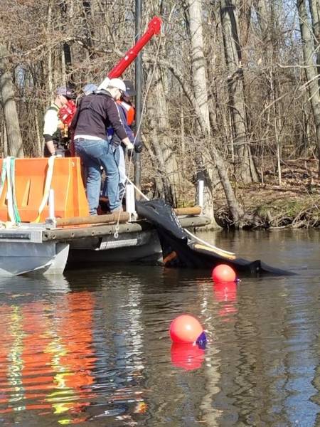 Forscher benutzen eine Winde, um einen Abschnitt des Unterwasserölbarrieresystems vom Kalamazoo Fluss, Mich. Am Mittwoch, den 25. April 2018 zurückzuholen. Sand gefüllte Plastikverkehrsbarrikaden hielten das Sperrensystem auf dem Flussunterseite, während Festmachungsbojen den Standort der markierten Prüfung. (US Coast Guard Foto mit freundlicher Genehmigung von Forschungs- und Entwicklungszentrum)