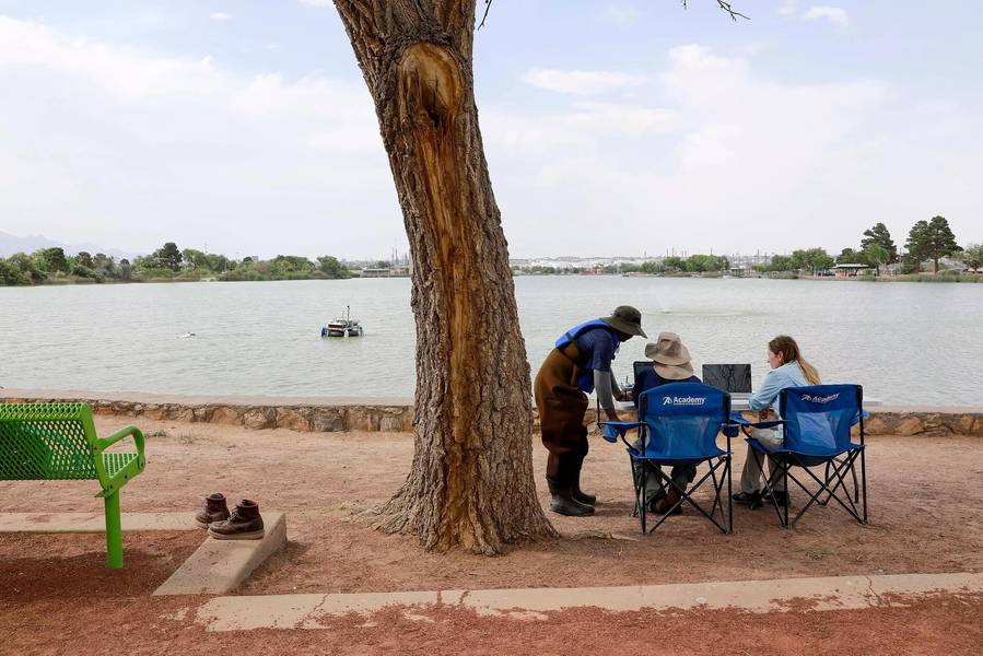 Da esquerda para a direita: Jayanga Thanuka Samarasinghe, estudante de doutorado da UTEP, o ex-aluno Fernando Sotelo e a professora assistente Laura Alvarez observam o barco da costa enquanto ele mapeia o terreno subaquático do Lago Ascarate. Crédito: Universidade do Texas em El Paso.