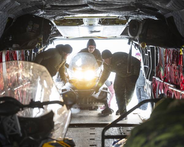 ノースウエスト準州イヌヴィクで行われたNANOOK-NUNALIVUT作戦の一環として、第1カナダ・レンジャー・パトロール隊のメンバーとCH-147Fチヌークの乗組員アンドリュー・ドイチュ軍曹が、スキー着陸場（SLA）キャンプに向けて離陸前にスノーモービルに荷物を積んでいる。写真提供：ジェイコブ・ハンロン伍長、カナダ軍写真
