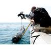 A civilian contractor steadies a M18 Mod 2  Kingfish Unmanned  Underwater Vehicle (UUV) as it is lifted with a crane onto the deck of an  11-meter rigid-hull  inflatable boat.  (U.S. Navy photo by Mass Communication Specialist 2nd Class Blake Midnight/Released)