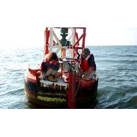 Max Ivanov and Scott Mowery with NOAA's Center for Operational Oceanographic Products and Services install an improved current sensor system on a navigation buoy in Chesapeake Bay. The system transmits real-time current speed and direction observations via satellite to help mariners more safely navigate busy shipping channels. (Photo: NOAA)
