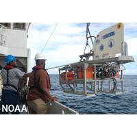 Two people deploy a towed camera system from a research vessel at sea. (Image credit: NOAA)