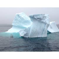 Small experimental unmanned surface craft conducting experiments near an iceberg.