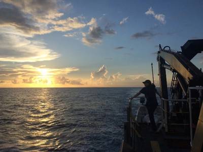 Emily Narrow, mission videographer, enjoys the sunset over the Pacific Ocean from the back deck of NOAA Ship Okeanos Explorer during the NOAA Ocean Exploration mission: Discovering the Deep: Exploring Remote Pacific Marine Protected Areas in 2017. Credit: NOAA Ocean Exploration
