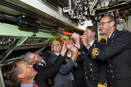 'Commodore Hans Lodder and Sytze Voulon of Imtech Marine Netherlands are cutting the cable in de commandcenter of Zr.MS. Zeeleeuw. From left Henk Jan Vink (TNO Director defence research), Commander Jouke Spoelstra, Sytze Voulon (Managing Director Imtech Marine Netherlands), Captain Marc lsensohn, Commodore Hans Lodder and Commander Danny van den Bosch. Photo: Ministry of Defence.’