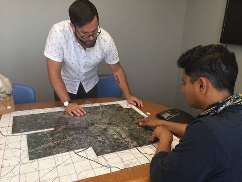 Jeremy Hoffman, scientist with the Science Museum of Virginia, (standing) and Vivek Shandas, professor at Portland State University, pore over a map of Richmond, Virginia, as they plan the routes for citizen scientists to collect heat data with a special sensor tool attached to their cars. The data will then be used to create a high-resolution map of the city’s hottest neighborhoods, which will provide information for cooling projects, tree planting and other climate action strategies. Photo cou