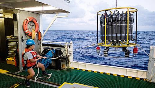 A marine technician hauls in the CTD (conductivity, temperature, and depth) rosette on a research cruise in the Sargasso Sea. © Maya Thompson