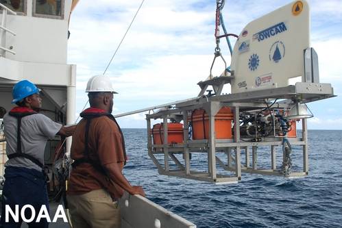 Two people deploy a towed camera system from a research vessel at sea. (Image credit: NOAA)