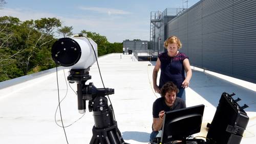 WHOI scientist Anna Michel and WHOI engineer Jason Kapit test a prototype long-range laser spectroscopy system. One telescope shoots out a laser beam that is recorded by the downstream telescope. In between, methane gas in the air absorbs some of the laser light. The more methane in the air, the less light arrives at the far end. (Photo by Ken Kostel, WHOI)