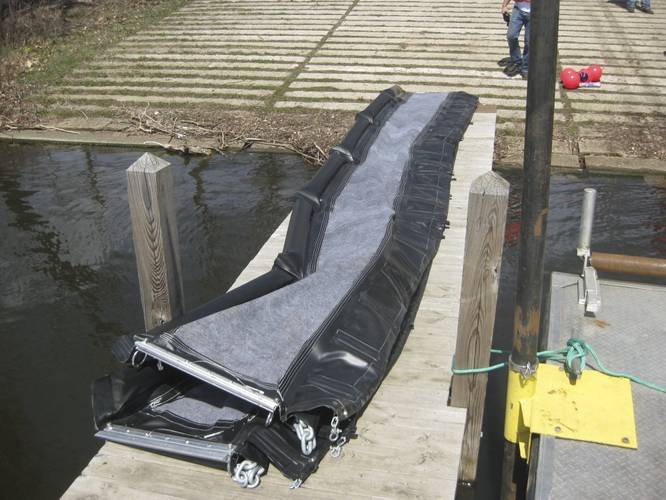 A 25-foot section of inland underwater oil barrier is laid out on a dock prior to deployment, Monday, April 23, 2018, in Kalamazoo, Mich. The three-foot high barrier is made of PVC and X-Tex fabric, and is designed to let water flow through while trapping oil. Weighted chains and scour flaps prevent oil and sediment from flowing underneath the barrier. (U.S. Coast Guard Photo courtesy of Research and Development Center)