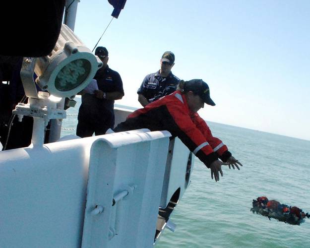 After a ceremony last month on board NOAA Ship Thomas Jefferson, Ensign Eileen Pye lays a wreath over the waters where USCS Robert J. Walker sank. (Credit: NOAA)