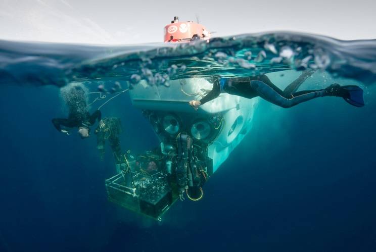 Atlantis crew members Patrick Neumann and Allison Heater assist in the recovery of Alvin following a test mission. They attach safety lines to support Alvin’s payload basket before it is lifted from the water. (Photo by Chris Linder, Woods Hole Oceanographic Institution)