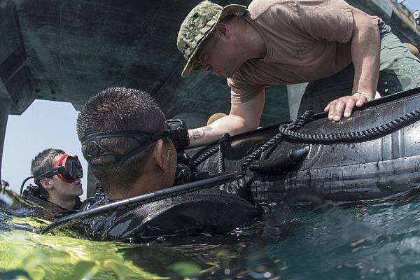 Construction Mechanic 1st Class Matt Ramirez, assigned to Underwater Construction Team (UCT) 2, checks the bottle pressures for Equipment Operator Seaman Recruit Adam Porras and a member of a Royal Thai Navy (RTN) during a dive at the Thung Prong Pier in Sattahip, Thailand for Exercise Cobra Gold 2018. (U.S. Navy photo by Alfred A. Coffield)