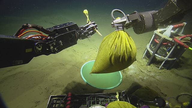 Cutting the bag to release glass beads in the caisson (Copyright: 2018 ONC/OET/Nautilus Live)