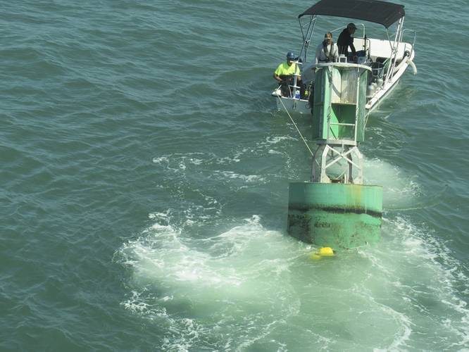 A diver boat tows a buoy with attached eco-mooring line toward divers awaiting to fasten it to one of the anchors (Photo courtesy of the U.S. Coast Guard)