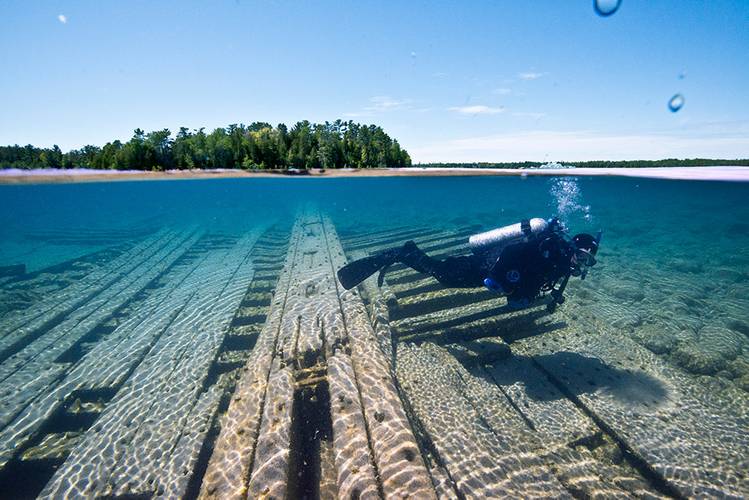 A NOAA diver swims over the shipwreck site of the wooden two-masted schooner Portland within Thunder Bay National Marine Sanctuary. (Photo: NOAA)