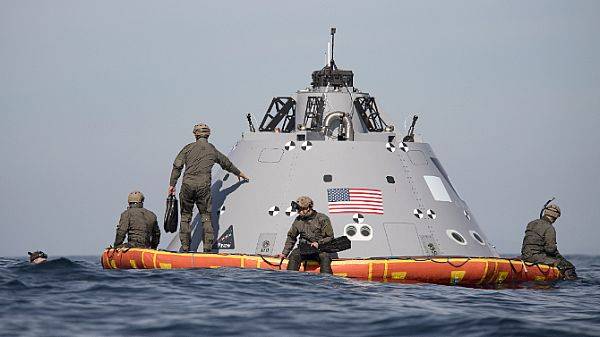 U.S. Navy divers assist NASA and USS Anchorage recover a mock-up capsule designed to roughly simulate the size, shape, mass and center of gravity of the Orion crew module that will splash down in the Pacific Ocean following Exploration Mission-1 planned for Dec. 2019. (U.S. Navy photo by Abe McNatt)