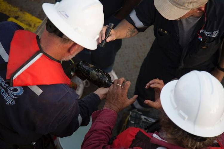 Endurance Exploration Group and Eclipse Group crewmen investigate a bottle recovered from the wreck of Steamship Connaught. (Photo: Endurance Exploration Group)