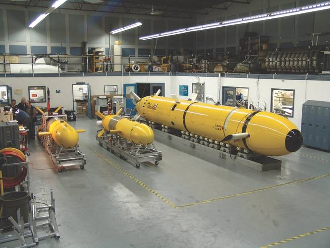 International Submarine Engineering (ISE) and the Canadian Department of National Defense developed Theseus (pictured in the ISE Shop with Explorer AUV and the prototype AUV ARCS) to lay fiber-optic cable under the Arctic ice pack. The vehicle was deployed to the Arctic in 1995 and 1996. In 1996, several 220 km cables were laid in 600 meter water depths under a 2.5 meter thick ice pack, establishing an AUV endurance record of over 60 hours – all under ice. (Photo: ISE)