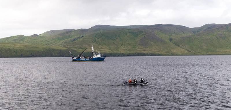 A dive team investigates sonar targets collected via the REMUS 100 AUV,  with RV Norseman II sailing in the background (Photo: NOAA)