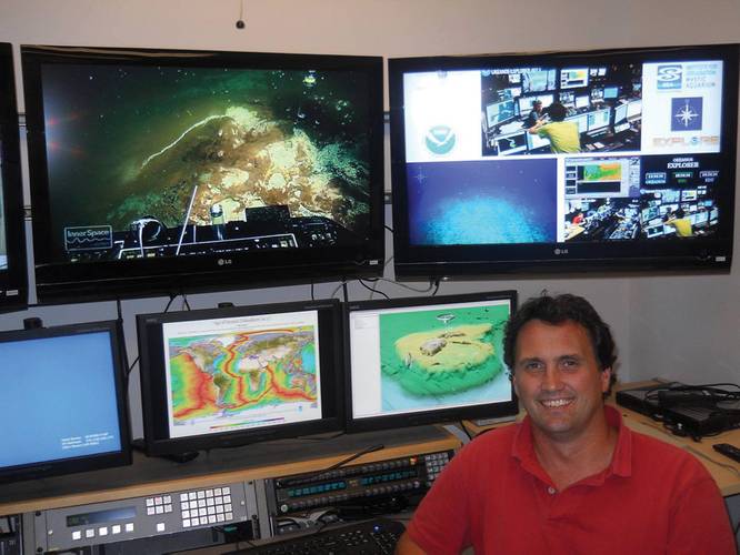 Prof. Dwight Coleman, a marine research scientist at URI’s Graduate School of Oceanography, and Director of the Inner Space Center, sits in front of a bank of monitors streaming live video feeds from remote research ships. 
