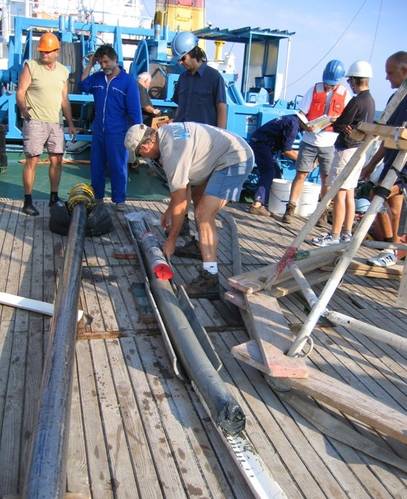 WHOI researcher Alan Gagnon, Marco Coolen (center, in blue safety helmet), and the crew from the Bulgarian research vessel Akademik sample the sediment core that was used for this study. (Photo courtesy Dimitri Dimitrov from the Institute of Oceanology, Bulgarian Academy of Sciences (IO-BAS))