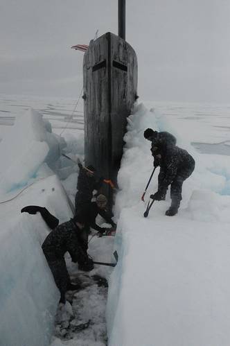 Sailors aboard the fast attack submarine USS Seawolf remove arctic ice from the hull after surfacing at the North Pole. (U.S. Navy photo)