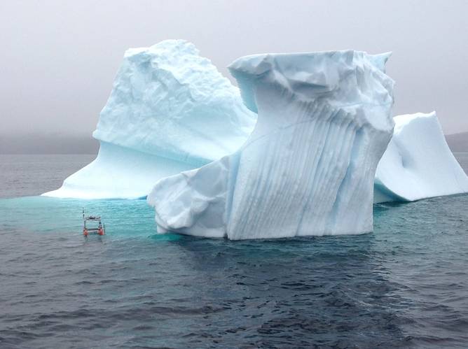 Small experimental unmanned surface craft conducting experiments near an iceberg.