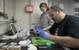 Expedition chief scientist Peter Girguis and Jennifer Delaney of Harvard University extract the viscera of a deep-sea clam collected by Alvin. A preserved sample will be sent to the Ocean Genome Legacy, which aims to archive the DNA of every marine species and make the data available to scientists. (Photo by Chris Linder, Woods Hole Oceanographic Institution)